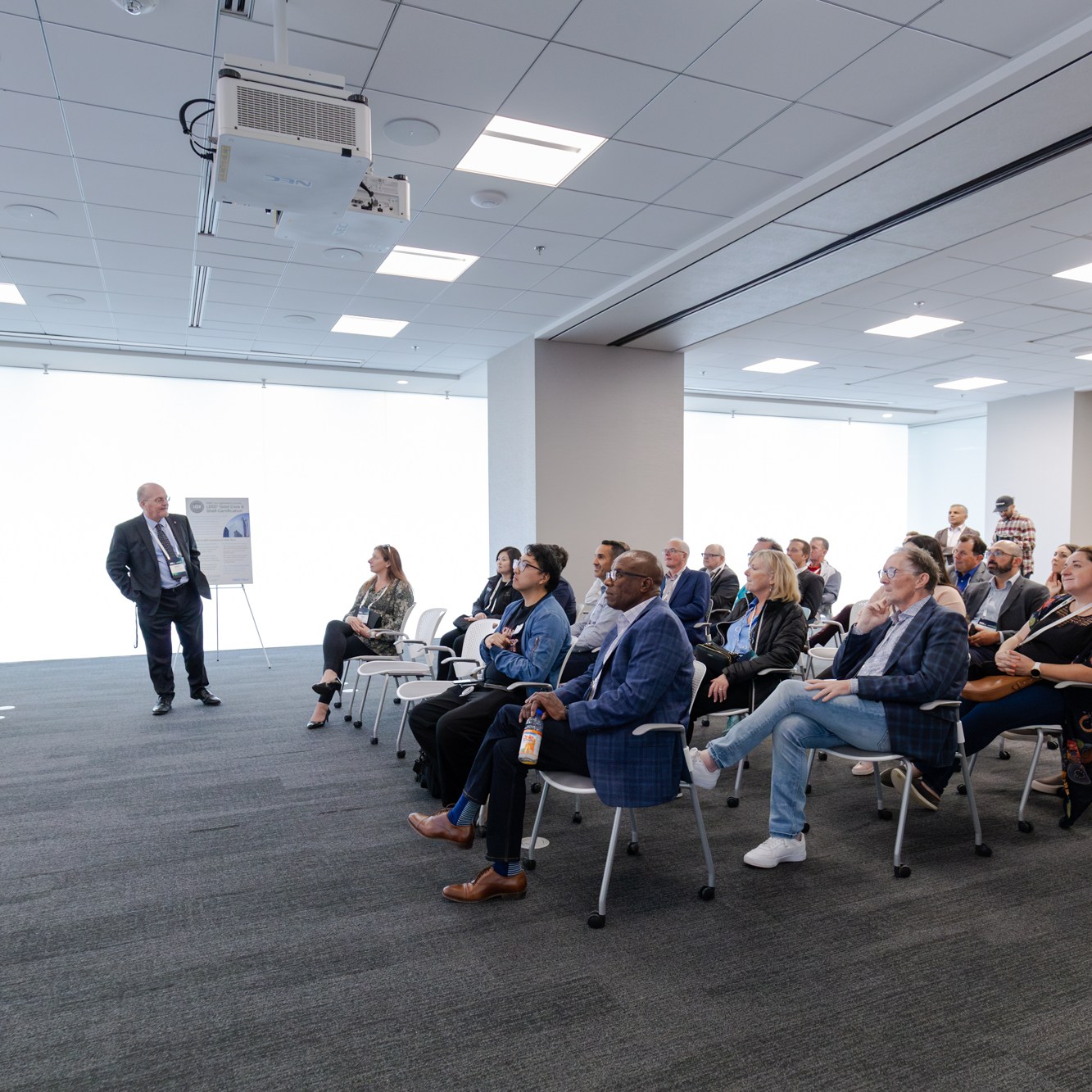 Image description: A group of participants listened to a speaker in a spacious, bright room.