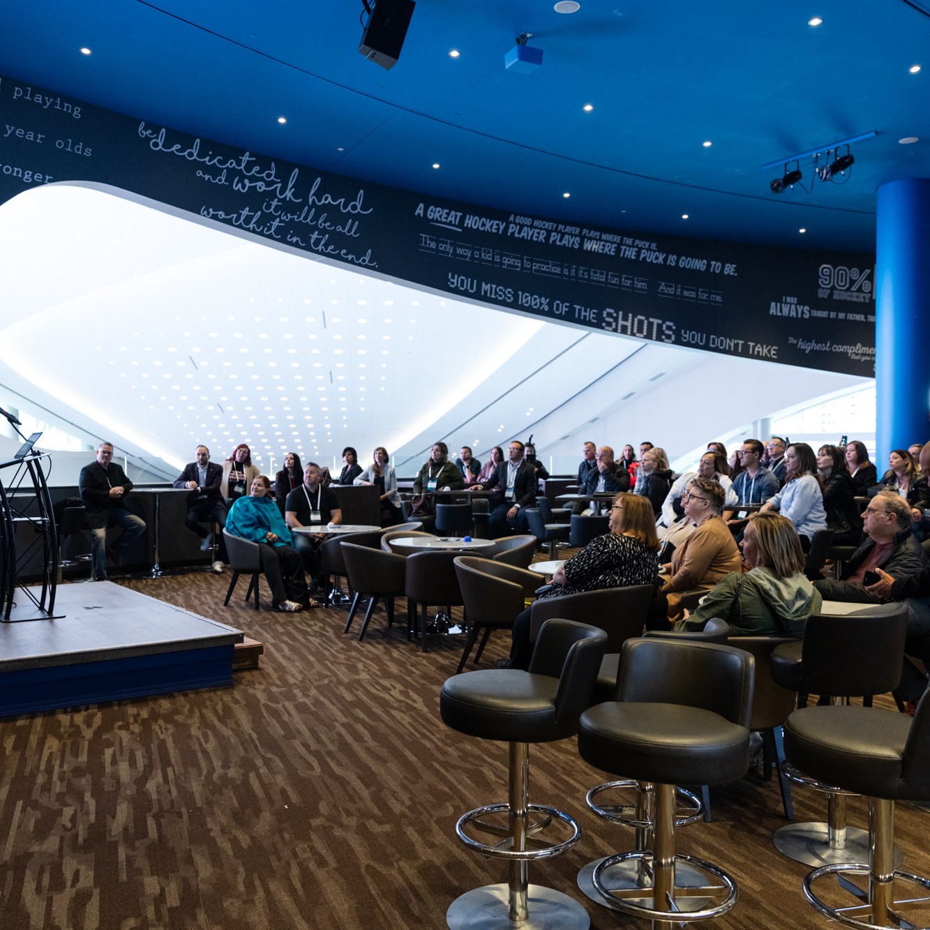 Image description: In the blue building, the participants listened carefully to the speaker.