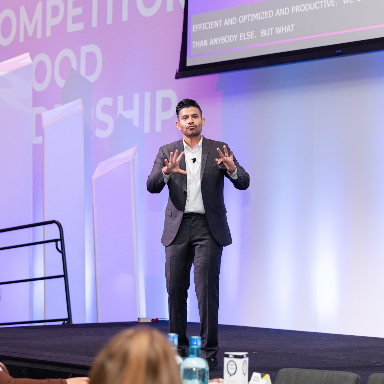 Image description: Keynote speaker in a dark gray suit and white shirt, giving a passionate speech.
