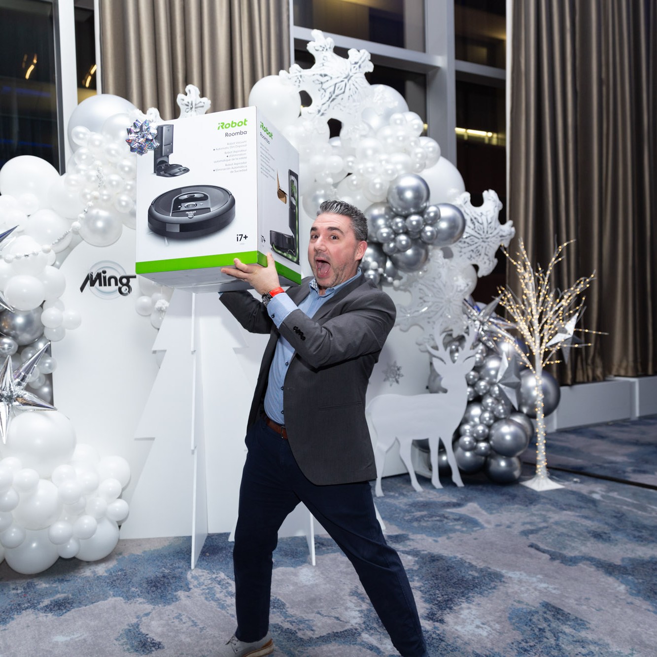 Image description: A man holds up an award he won at the year-end party and smiles at the camera. Text reads: irobot