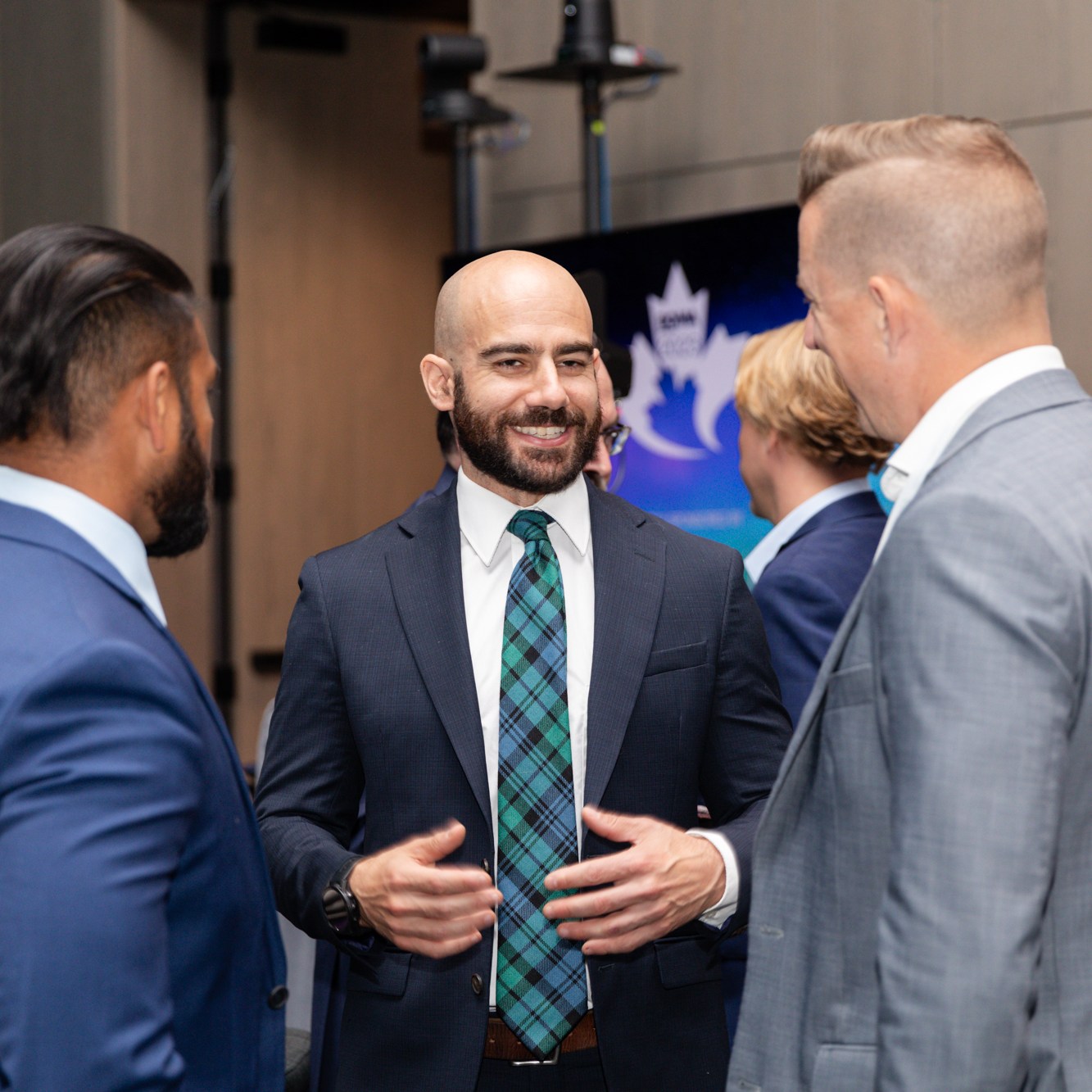 Three business men in blue, dark blue and light gray suits were chatting with each other.