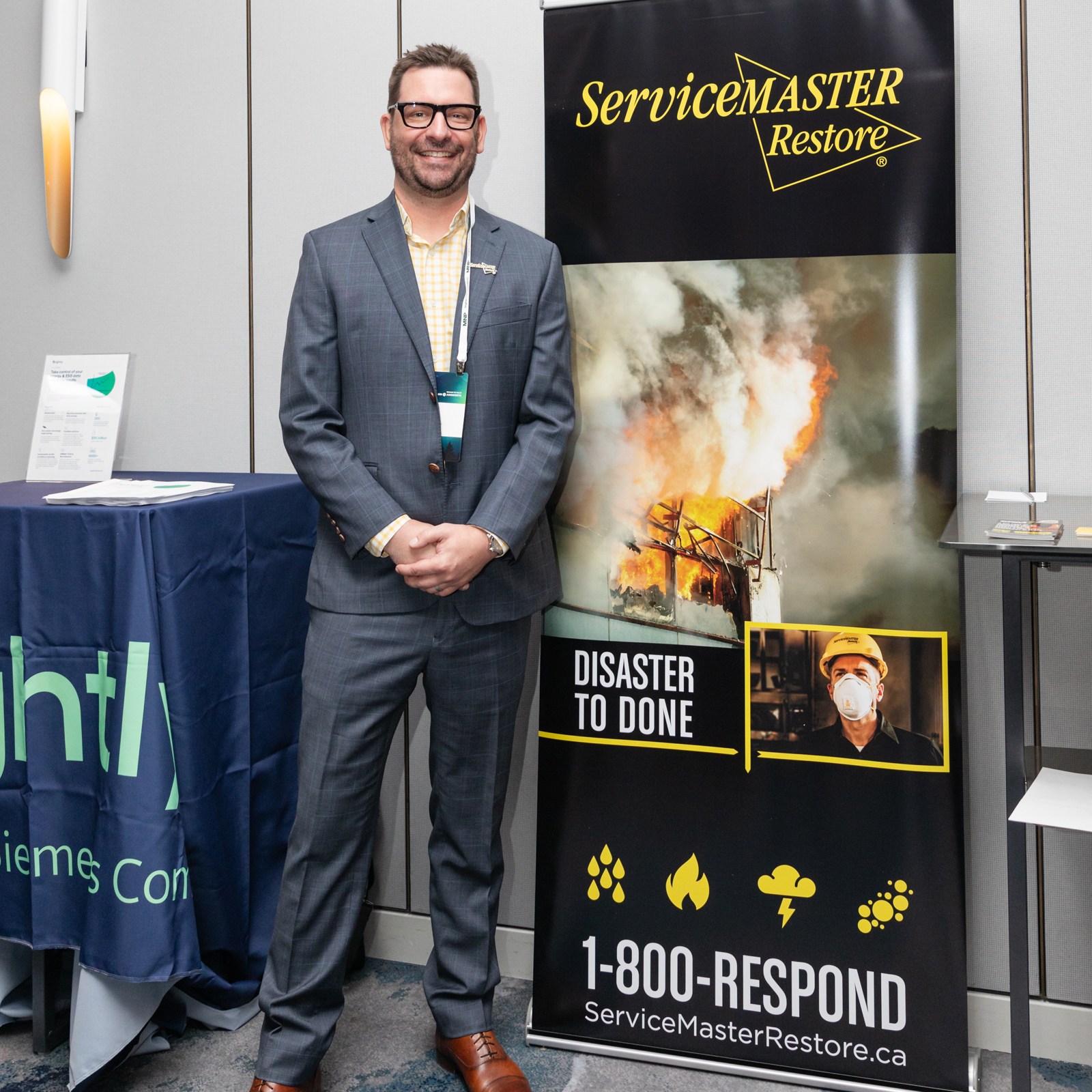 Image description: A man is standing in front of a billboard. Text reads: servicemaster restore, disaster to done, sermasterrestore.ca