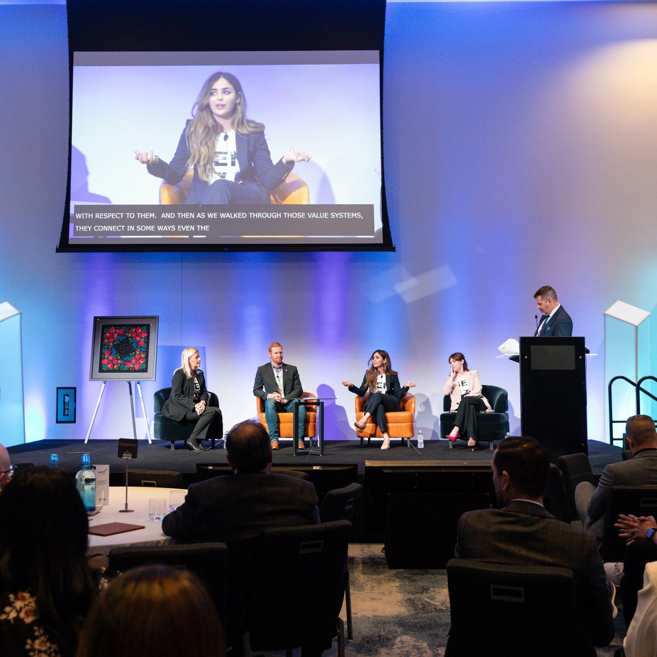 Image description: Four speakers spoke on the stage. The participants sat in the audience.